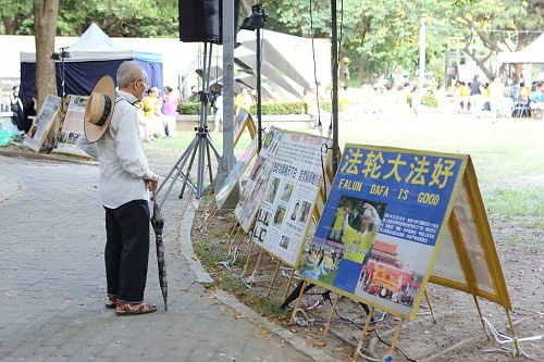 图12：老先生驻足在展板前关心自焚伪案真相