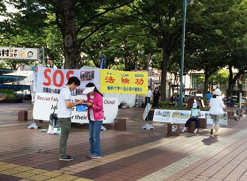 在爱知县名古屋市最繁华地段之一的荣（Sakae），行人在反中共活摘法轮功学员器官的签名簿上签字。