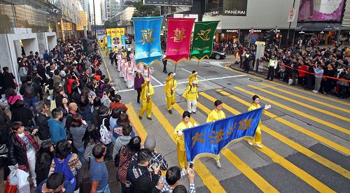 法轮功阵容庞大整齐的游行队伍吸引中西游客及港民驻足观看，纷纷举起相机、手机拍照。