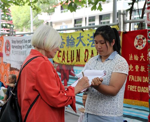 图1-4：二零一五年十二月三十一日晚，在墨尔本市中心迎接新年到来的人们，驻足在法轮功学员征签的真相点，签名举报迫害元凶江泽民，呼吁制止中共迫害。