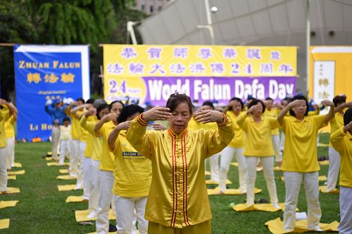 图2-3：新加坡法轮功学员集体炼功庆祝世界法轮大法日，与民众分享大法的美好。