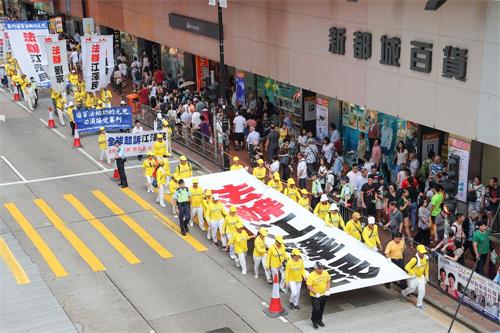 '图4～5：约一千名法轮功学员昨日在港岛区举行反迫害19周年集会游行，呼吁停止迫害、法办元凶。有陆客惊见“法办江泽民”横幅，表示支持。'