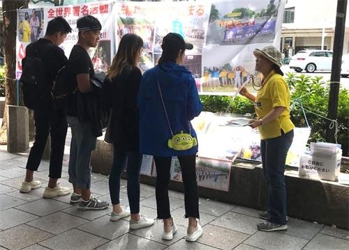 '图1：法轮功学员向观看展板的民众讲真相'