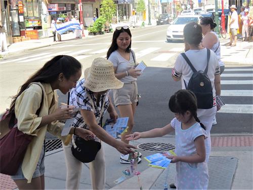 '图6：一位年轻女士高兴地接过象征平安与幸福的小莲花。'