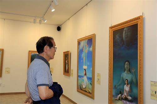 '图9：77岁的姜明德先生很高兴通过“真善忍国际美术展”了解到了修炼身心的法轮功，他对修炼产生了兴趣。'