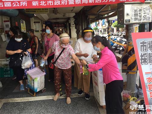 '图1～2：法轮功学员在市场门口为民众量体温并借机传递真相资料和小莲花'